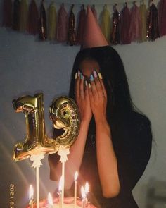 a woman covering her face in front of a birthday cake