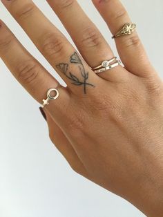 a woman's hand with three different rings on it and a butterfly tattoo on the ring