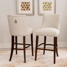 two white upholstered barstools in front of paintings