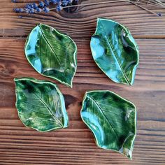 three green leaf shaped dishes sitting on top of a wooden table