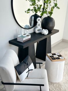 a black and white living room with a round mirror on the wall next to a chair