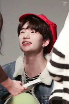 the boy is wearing a red hat and looking up at something in front of him