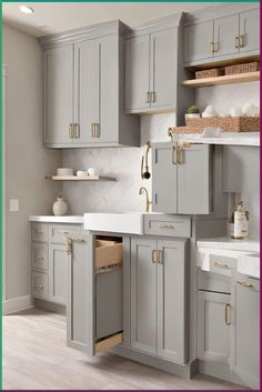 a kitchen with gray cabinets and white counter tops, gold pulls on the cabinet doors