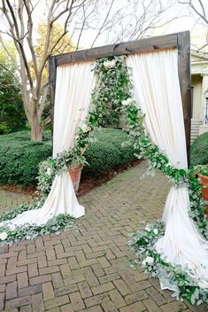 an outdoor wedding arch decorated with greenery