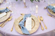 the table is set with gold and blue place settings, silverware, and napkins