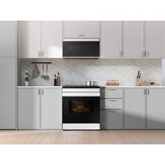 a kitchen with an oven, microwave and counter tops in white cabinets on the wall