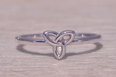 a silver ring with two intertwined hearts on it's sides, sitting on a wooden surface