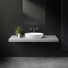 a white sink sitting on top of a counter next to a plant in a vase