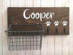 a wooden sign that says cooper with paw prints and hooks on the side of it