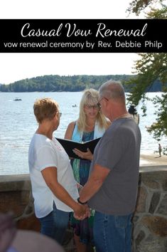 a man and woman holding hands while standing next to each other in front of the water