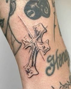 a close up of a person's arm with tattoos on it and a cross