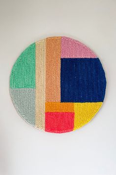 a multicolored circular artwork hanging on the wall in front of a white wall