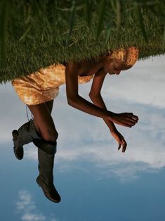 a man is hanging upside down from the grass on top of his head and feet