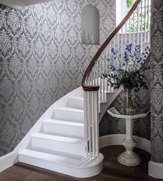 there is a vase with blue flowers on the table next to the stairs in this house