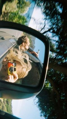 a woman taking a selfie in the side mirror of a car