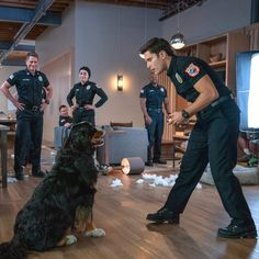 a man in uniform standing next to a black and brown dog on a hard wood floor