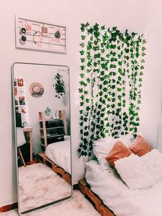 a mirror sitting next to a bed in a room with plants on the wall behind it