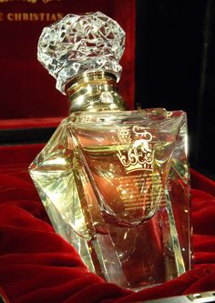 a bottle of perfume sitting on top of a red velvet covered table