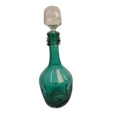 a green glass bottle with a white face on it's top is shown against a white background