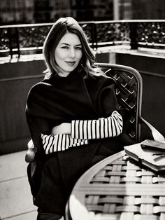 black and white photograph of a woman sitting at a table with her arms folded out