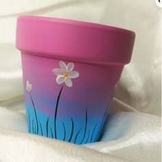 a painted flower pot sitting on top of a white cloth