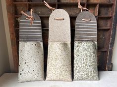 three cement salt and pepper shakers sitting on top of a counter next to a wooden shelf