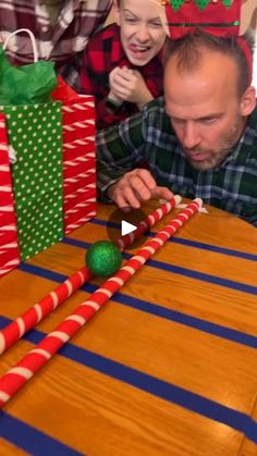 a man and woman sitting at a table with candy canes