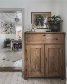 a wooden cabinet sitting on top of a hard wood floor next to a dining room table