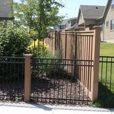 the fence is made of metal and has a black gate in front of some houses