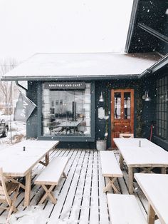 the outside of a building with tables and benches covered in snow