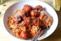 a plate of spaghetti with meatballs and parmesan cheese on the side next to a measuring cup