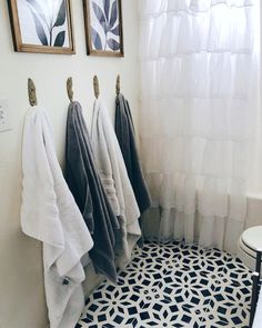 three towels hanging on hooks in a bathroom