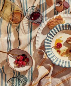 a table topped with plates and bowls filled with desserts next to glasses of wine