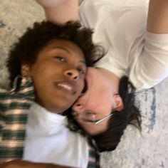 two people laying on the floor with their heads close to each other and one person taking a selfie