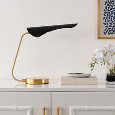 a table lamp sitting on top of a white dresser next to a potted plant