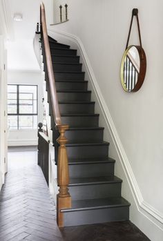 the stairs are black and white in this hallway, with a mirror on the wall