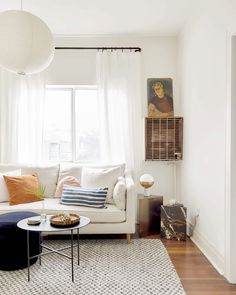 a living room filled with furniture and a white couch in front of a large window