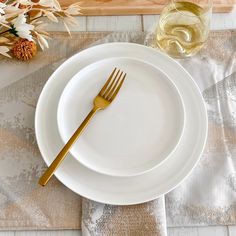 a white plate topped with a fork next to a glass of wine