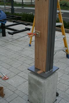 a tall wooden object sitting on top of a cement block