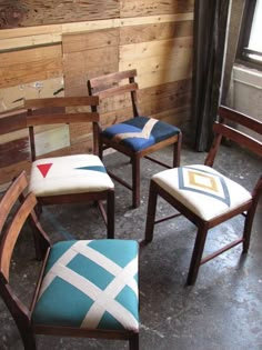 three wooden chairs sitting next to each other in front of a wood paneled wall