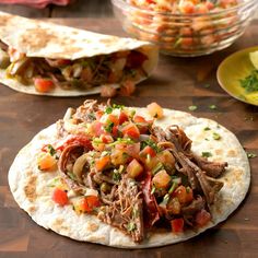 two tortillas filled with meat, vegetables and sauces on a wooden table