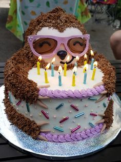 a birthday cake with a slotty bear wearing sunglasses and holding a lit candle in its mouth