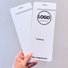 two white business cards being held up by someone's hand with the logo on them