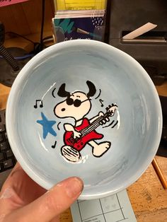 a person holding a bowl with a cartoon character painted on the front and side of it