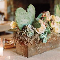 an arrangement of flowers and succulents in a wooden box on a table