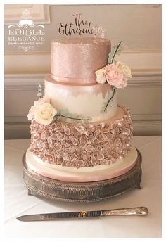 a three tiered wedding cake with pink flowers on top and the bride's name on top