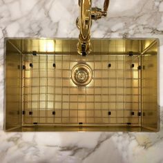 a kitchen sink with gold fixtures and marble counter top