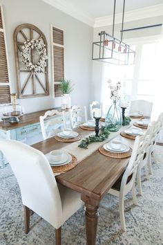 the dining room table is set with white chairs and place settings for four people to sit at