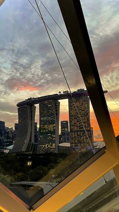 the city skyline is seen through a glass window at sunset in singapore's central business district