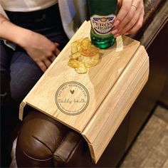 a person holding a wooden box with chips in it and a bottle of beer on top